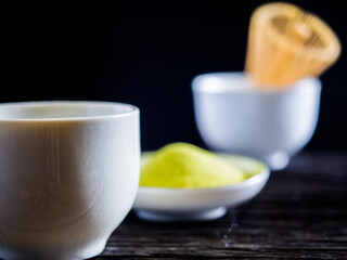 close up green tea, matcha power and whisk a cup of hot green tea on wooden table.traditional japanese drink