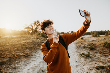 Reisende macht Selfie und zeigt mit den Fingern das Peace-Zeichen in die Kamera 