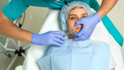 Close up cosmetologist hands in gloves introducing Hyaluronic acid in patient lips with perfect...