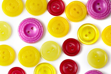 Colorful yellow red and pink buttons on a white background. Old vintage buttons close up. Copy space. Top view. Background of buttons. Flat lay. close-up