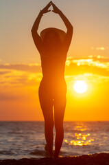 Fototapeta na wymiar Silhouette of a girl in a swimsuit with a hat near the sea