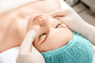 The girl's face is being cleaned after spa procedures, close-up. Skin care, beautician, spa treatments, facial hygiene.