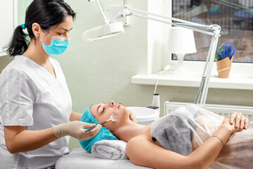 A beautician applies a mask to the face in a beauty salon. The concept of facial hygiene, cosmetic...
