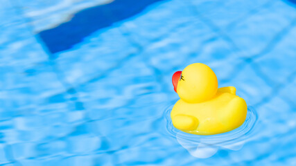 Plastic duck. Yellow kids rubber toy float in blue water of summer pool. Summer holiday poster.