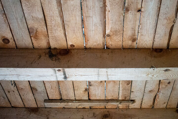 Grunge rough wooden ceiling in a perspective view with colorful stains of fungus and moist and jars in wood. Beamed ceiling in a shed or attic or old wooden cabin.