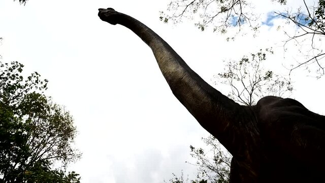 Artificial dinosaur sculpture decoration in the natural park garden.