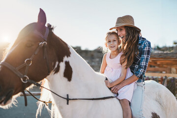 Mother and daughter riding a horse at ranch - Mother and child love
