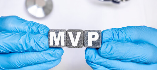 MVP Mitral valve prolapse - word from stone blocks with letters holding by a doctor's hands in medical protective gloves