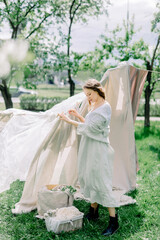 Girl Hanging Up Wet Laundry On Clothesline. The concept of unity girl with nature and the beginning of spring time with flowering trees. sunny day in village