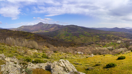 Panoramic green landscape with blue sky with clouds and high mountains in the background. Sierra...
