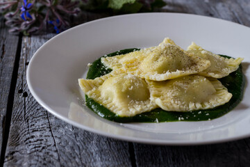 Ravioli stuffed with potatoes and carrots on a bed of borage puree with a sprinkling of Parmesan cheese and black pepper
