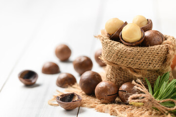 Dry Roasted Macadamia Nut in sack on white wood background,