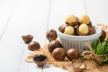 Dry Roasted Macadamia Nut in white cup on white wood background,Macadamia nuts are loaded with flavonoids and tocotrienols and rich in heart-healthy monounsaturated fats