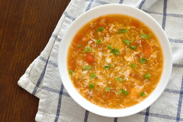 Tomato egg drop soup in a white bowl.   Traditional Chinese food.  Flat lay top view photo.  Food from above concept. 