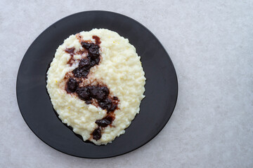 rice pudding with sour cherry jam, on a ceramic black plate