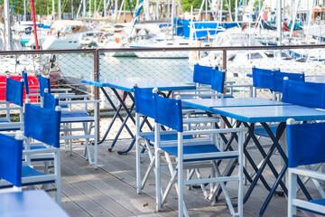 Empty tables in restaurant in front of the yachts harboor