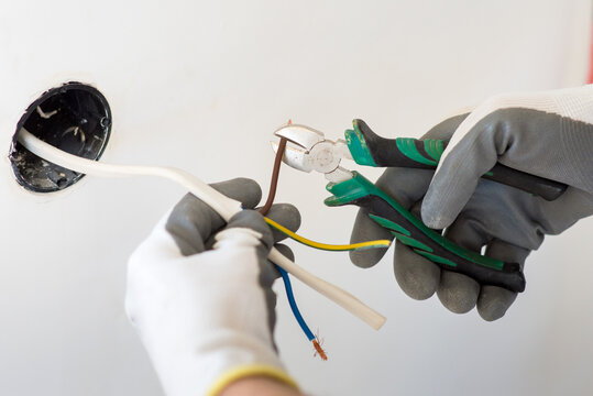 Repairman worker, cuts the electrical wire, during the installation of the outlet, close-up, home renovation