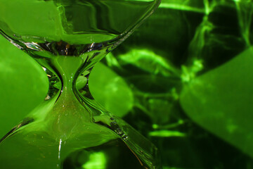 Macro photo, glass hourglass detail, shadows and bright green background.