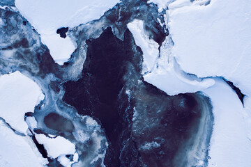 thawing in winter, flowing river in snow and ice, wildlife texture