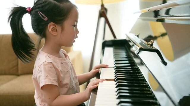 Medium close up shot of Asian girl toddler practice piano with happy and fun, Music class learning at home.