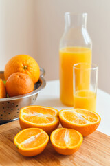 Glass of fresh natural orange juice on the table for a cheerful morning. Sliced juicy oranges for making fresh juice on a wooden board. Vitamin drink for breakfast. Healthy lifestyle, natural products