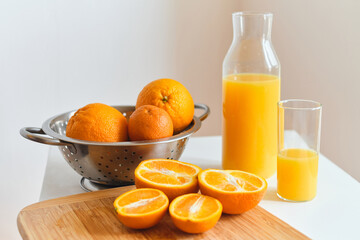 Glass of fresh natural orange juice on the table for a cheerful morning. Sliced juicy oranges for making fresh juice on a wooden board. Vitamin drink for breakfast. Healthy lifestyle, natural products