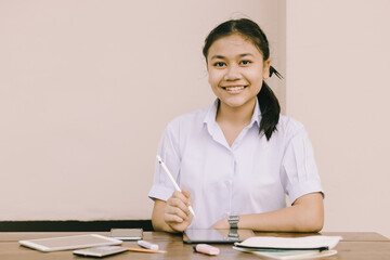 Asian Thai cute girl teen student school uniform happy smile using Tablet PC for E-Learning self isolated education happy smile concept
