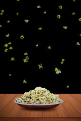 The popcorn in the bowl is isolated against a dark background of exploding or flying