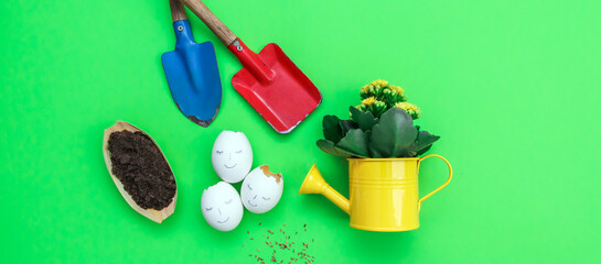 Gardening tools and watering can with flower on green