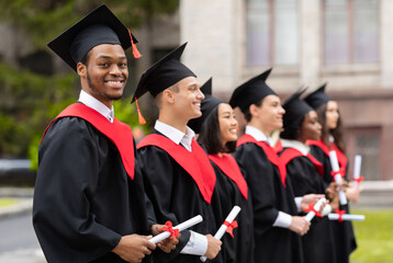 Diverse international students with diplomas attending graduation ceremony