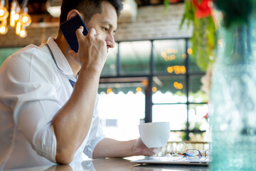 Businessman talking on phone while working on laptop.