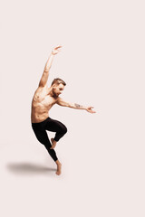Sexy shirtless young male ballet dancer wearing black leotard or tights dancing on white background
