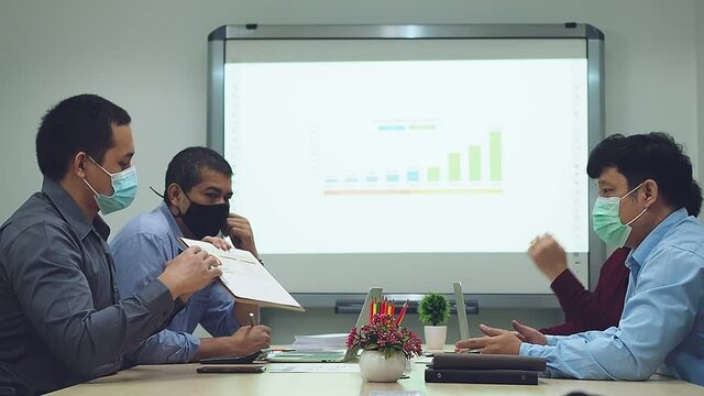 Businessmen wearing protective masks discussing and work together in meeting room. Social distance practice prevent coronavirus COVID-19.