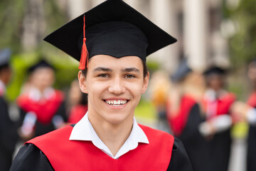 Closeup portrait of happy guy student wearing graduating costume