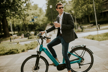 Young businessman on the ebike with takeaway coffee cup