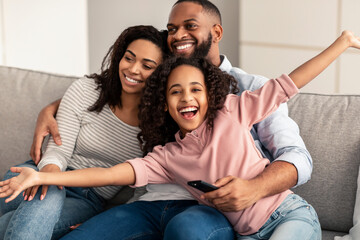 Happy young family watching television sitting on sofa
