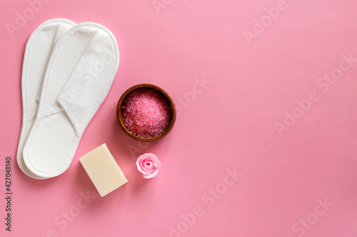 Natural spa set with disposable slippers, salt and soap on a pink background. Valentine's Day, birthday, mother's day, 8 March. Top view, flat lay.