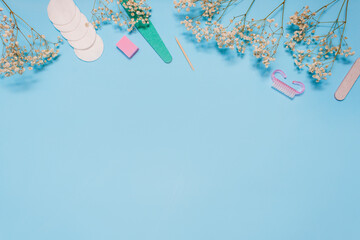 Manicure tools on a blue background are decorated with white gypsophila flowers. The concept of beauty. Copy space. top view