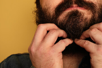 Cropped portrait of confident men with moustache standing over yellow wall.