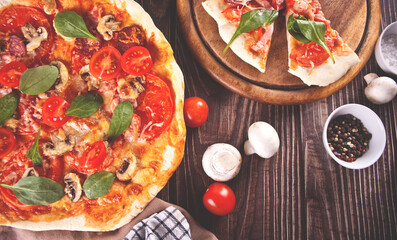 Homemade pizza with pepperoni sausage, bacon decorated spinach and ingredients on the background. Top view.
