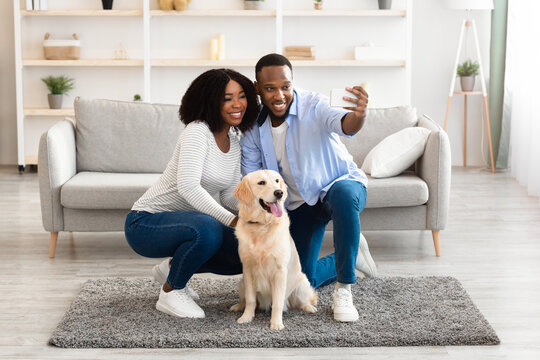 Young black couple taking selfie with dog at home