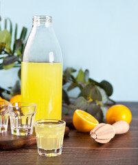 Italian drink lemon liqueur limoncello in a bottle and empty glasses on the wooden table