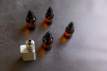 Vaping device e-cigarette electronic cigarette and liquid bottles on dark black stone shale...