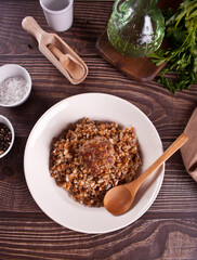 Buckwheat porridge with meat ball on the wooden table.