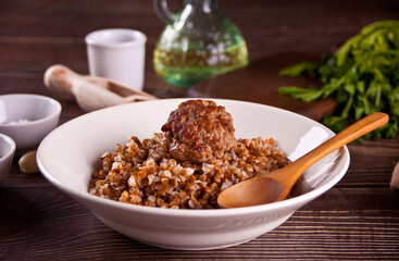 Buckwheat porridge with meat ball on the wooden table.