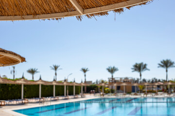 Sun umbrellas and sun loungers by the pool. Tropical vacation background