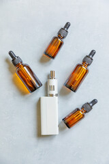 Vaping device e-cigarette electronic cigarette and liquid bottles on concrete stone grey background. Vape device for alternative smoking. Vaping shop concept. Gadget for vaper. Vaping accessories.