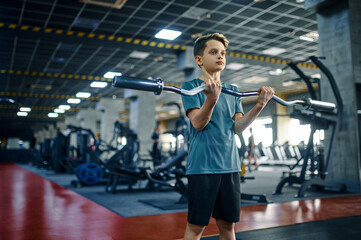 Youngster doing exercise with bar in gym