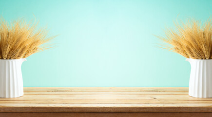 Wheat in vase on wooden table over blue background. Shavuot holiday decor mock up for design.