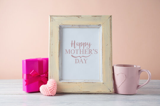 Mother's day concept with photo frame mock up, gift box and coffee cup on wooden table.
